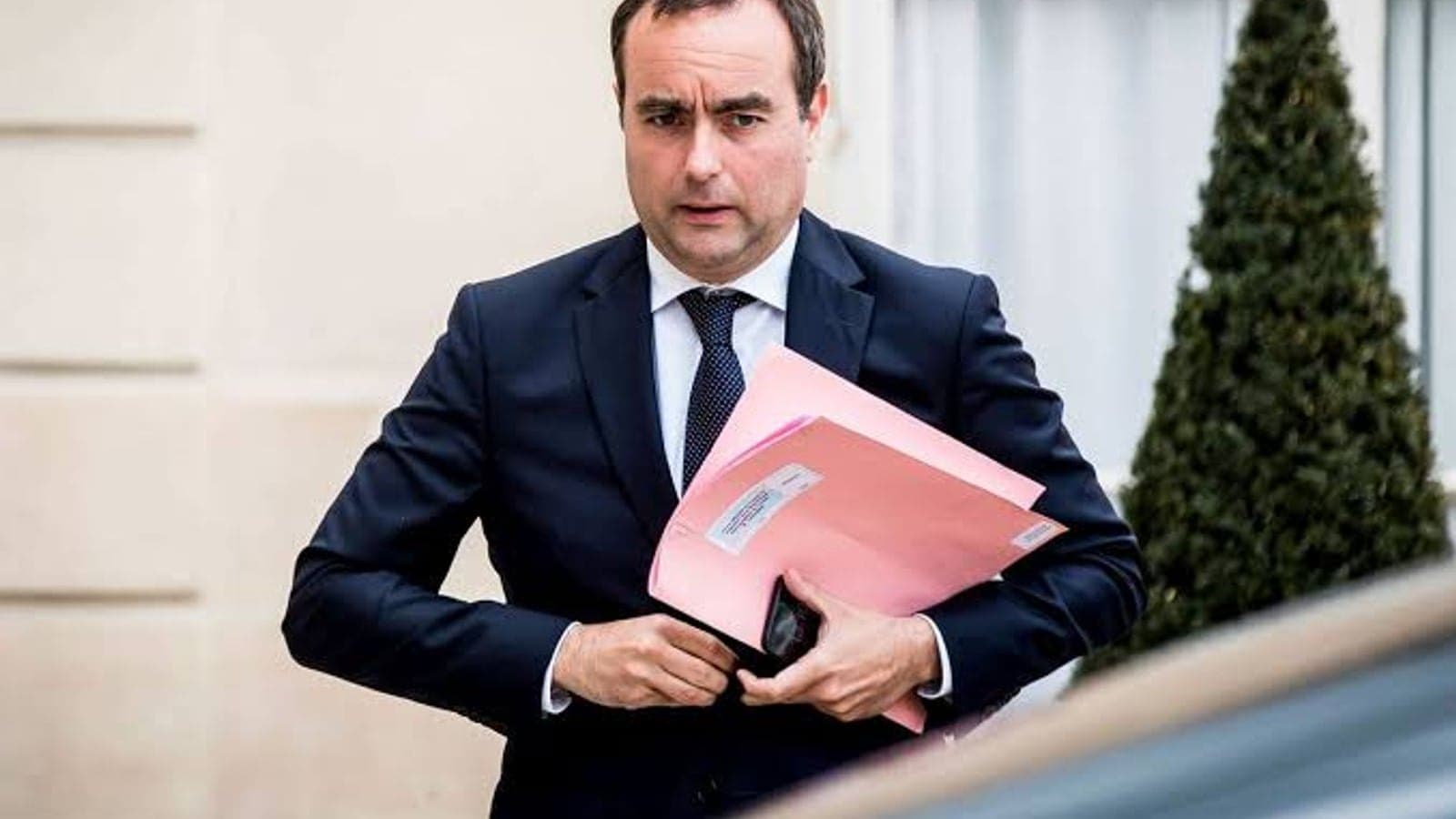 Sébastien Lecornu quittant un bâtiment gouvernemental, des dossiers sous le bras.