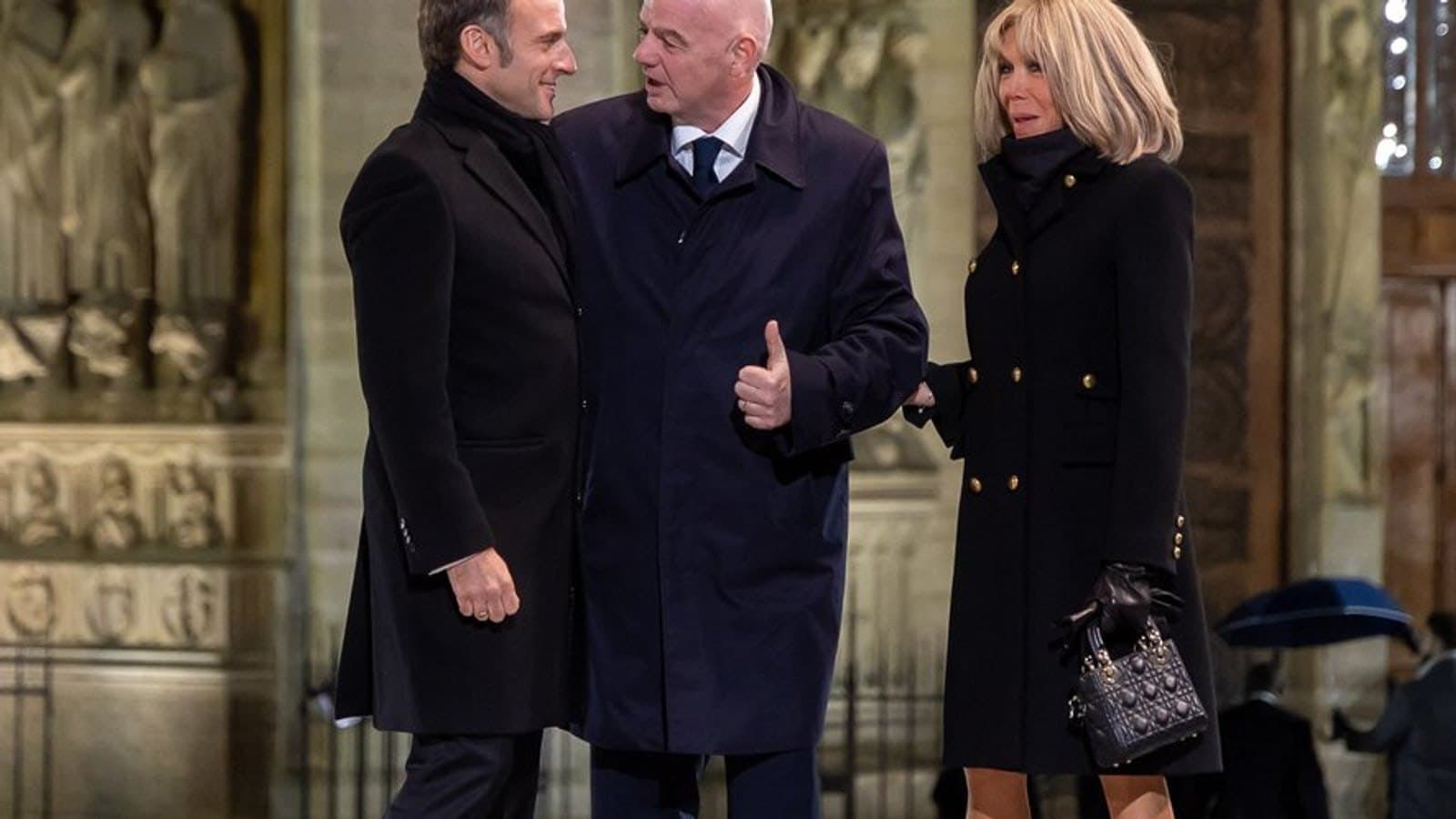 Emmanuel Macron speaking with Gianni Infantino, with Brigitte Macron alongside, inside a cathedral. Photo d'archive.