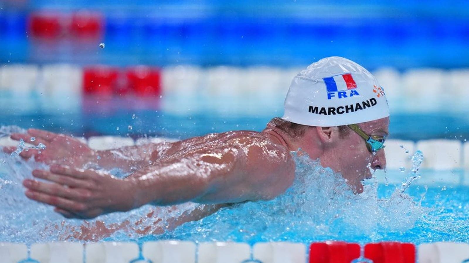 Leon Marchand en papillon, bonnet France, bras hors de l'eau en pleine nage.