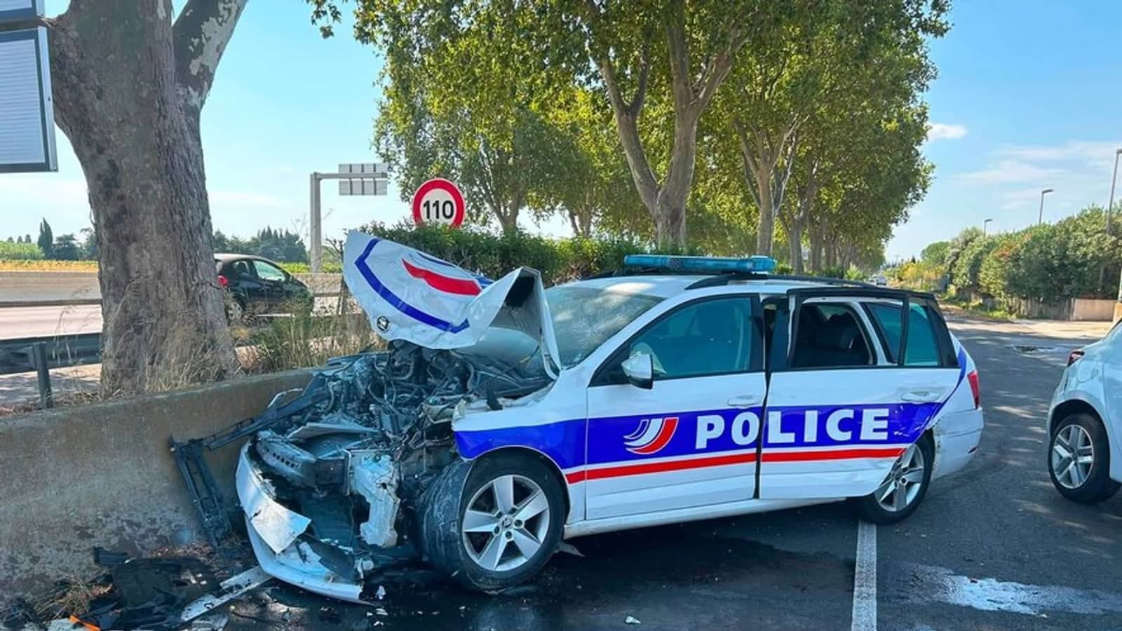 A wrecked police car with its front end destroyed at the roadside.