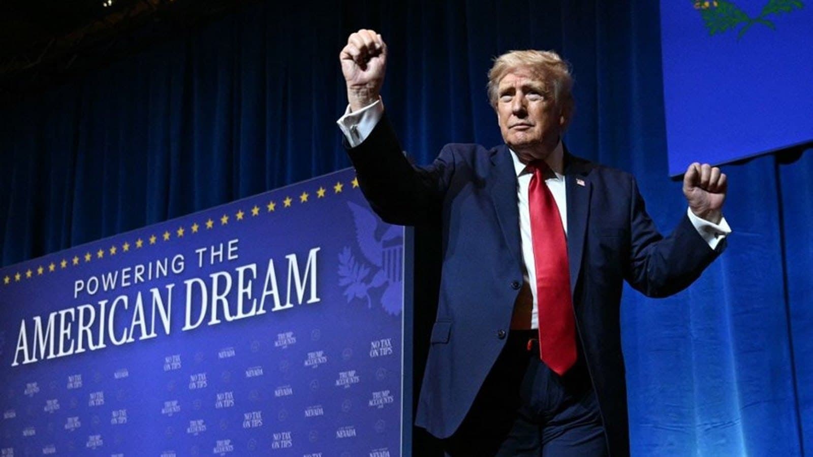 Donald Trump on stage with both fists raised at a campaign-style event.