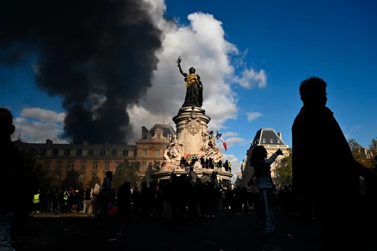 De la fumee s'eleve derriere la statue de la Place de la Republique a Paris lors d'une manifestation