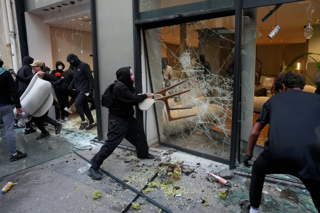 Des individus cagoules brisent la vitrine d'un magasin lors des emeutes en France