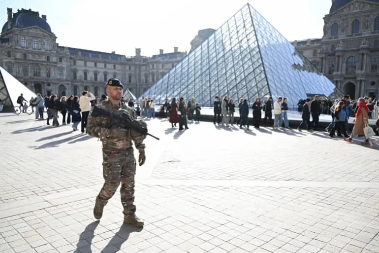 Un militaire en patrouille devant la pyramide du Louvre a Paris