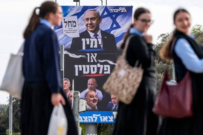 Des lyceennes passent devant un panneau electoral du Likoud en Israel
