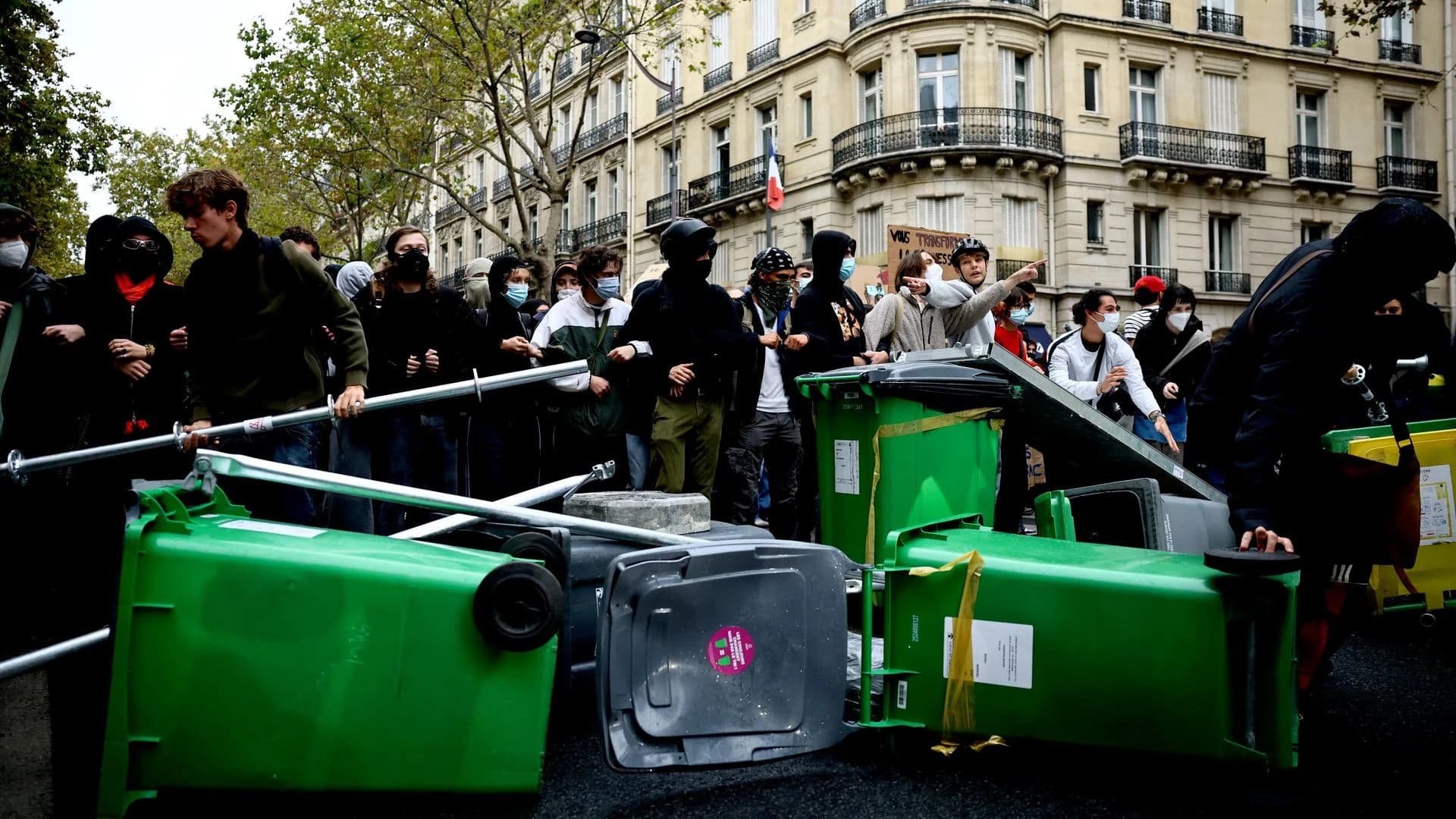 Protesters stand behind a barricade of bins during a demonstration in Paris