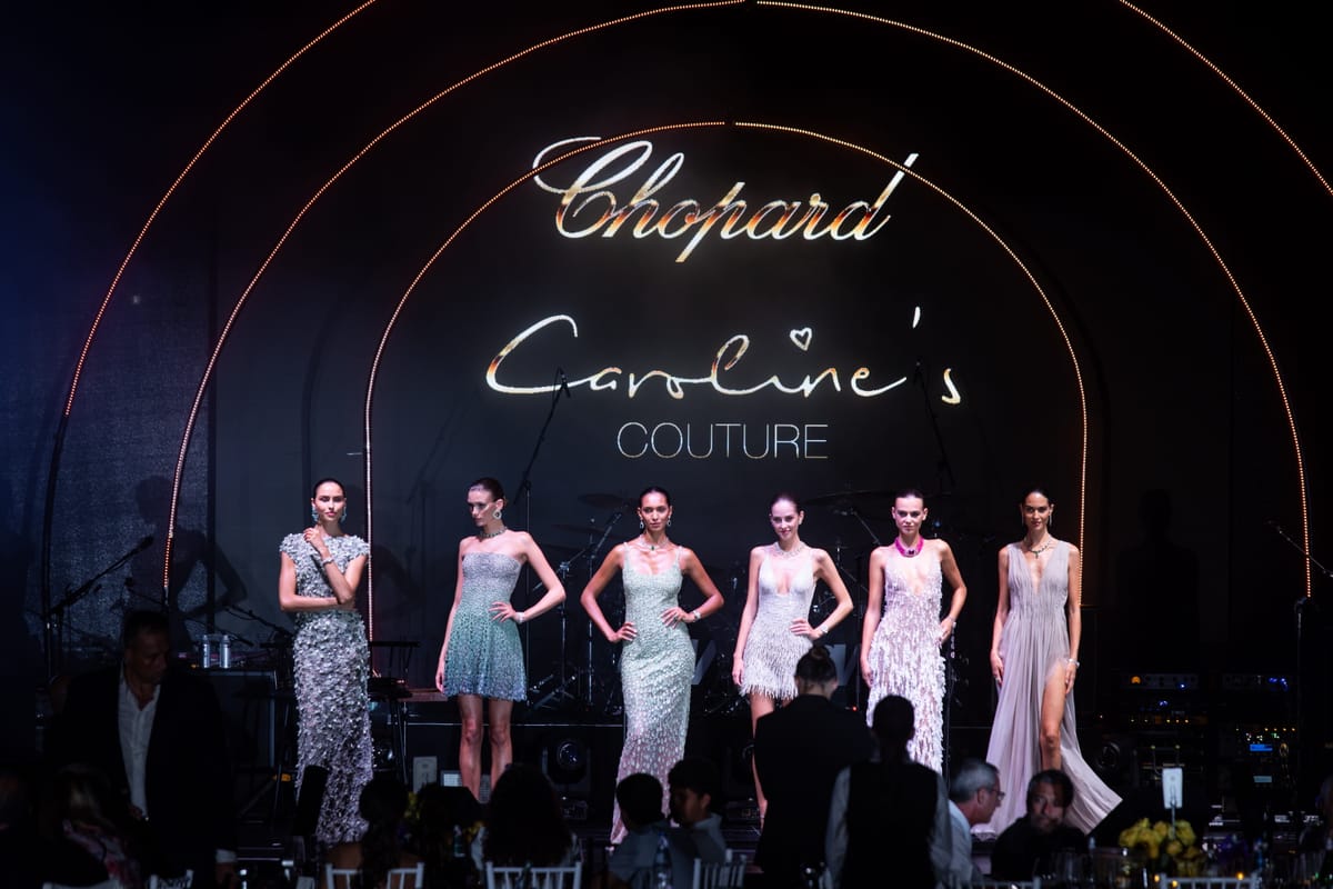 Models on stage beneath illuminated Chopard and Caroline's Couture signage.