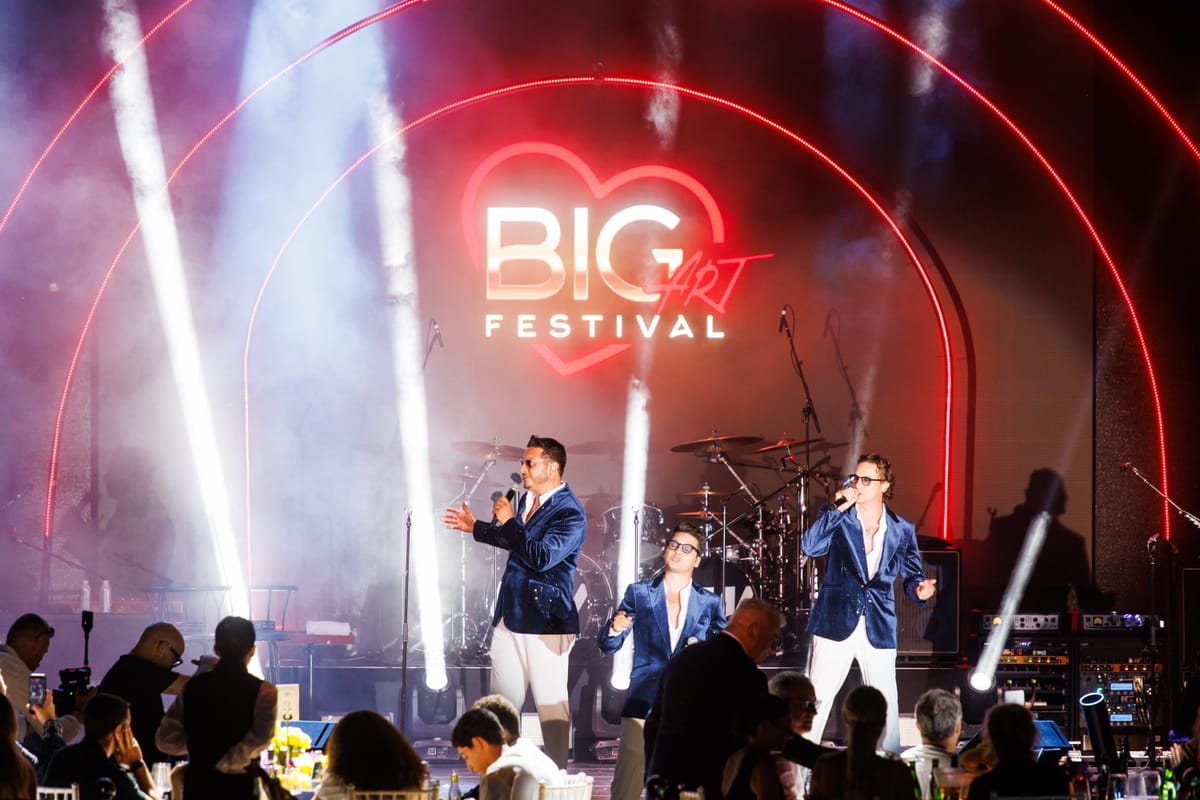 The Esteriore Brothers performing in blue jackets beneath the BIG ART Festival sign.